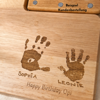 Beispiel einer Kundenbestellung: personalisiertes Schneidebrett mit Messer, graviert mit zwei Handabdrücken, den Namen Sophia und Leonie sowie «Happy Birthday Opi» als Geburtstagsgeschenk.