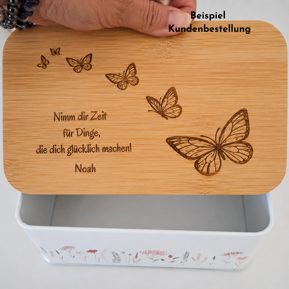 Beispiel einer Kundenbestellung: personalisierte Guetzlidose mit graviertem Bambusdeckel, Schmetterlingsmotiv, dem Namen Noah und dem Spruch «Nimm dir Zeit für Dinge, die dich glücklich machen!» als persönliches Geschenk.