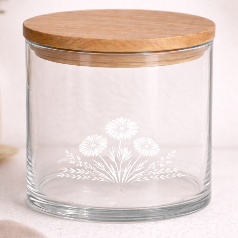 Runder Glasbehälter mit Holzdeckel und weissem Blumenmotiv, geeignet zur stilvollen Aufbewahrung von Lebensmitteln oder kleinen Gegenständen.