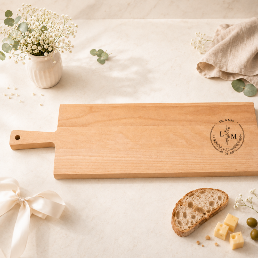 Personalisiertes Apérobrett aus Buchenholz mit Griff, graviert mit Namen Lisa und Mike, Initialen im Blumenkranz und Hochzeitsdatum, als Hochzeitsgeschenk dekoriert mit Brot und Käse